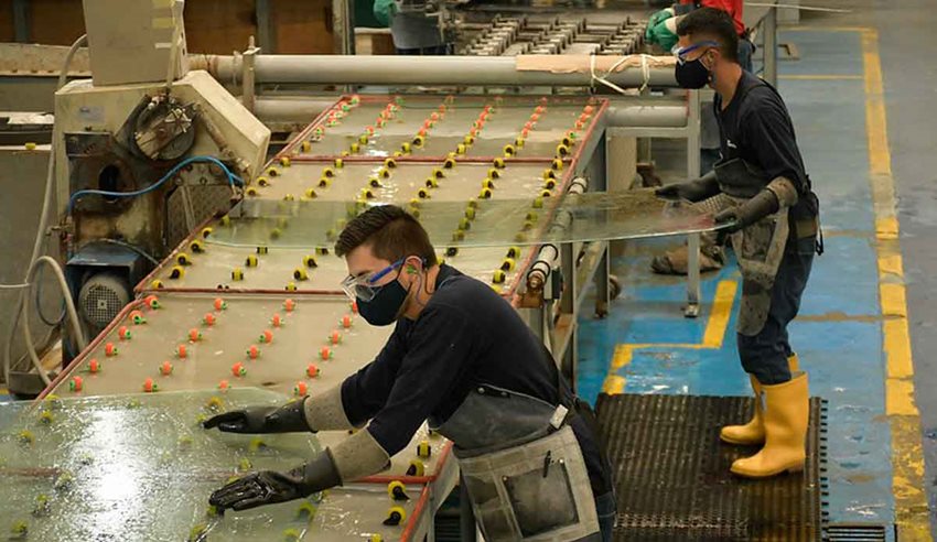 Hombres con elementos de seguridad trabajando en máquina industrial.
