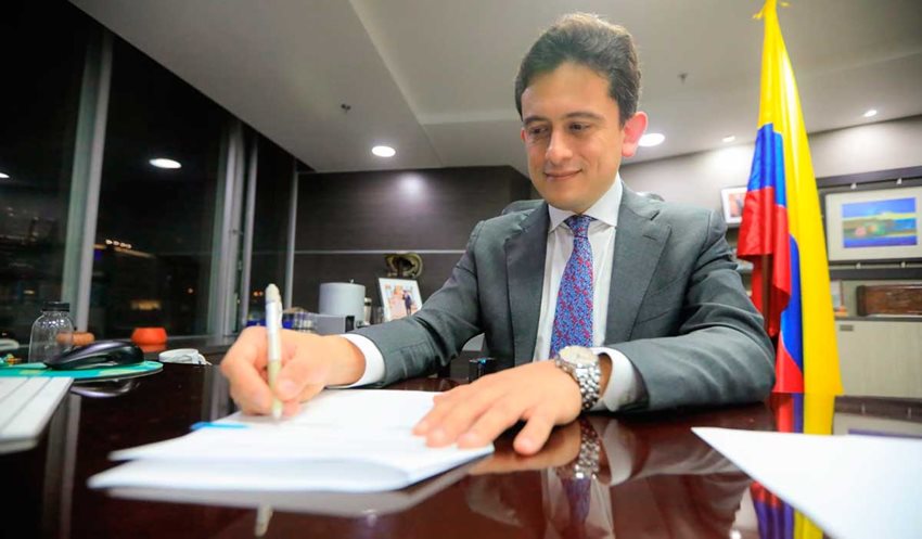 Ministro de Comercio, Industria y Turismo, Luis Carlos Reyes, firmando un documento en su oficina.