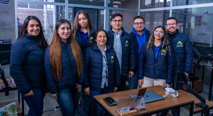 Cinco mujeres y tres hombres, con chaquetas azules oscuras, posando para la foto.