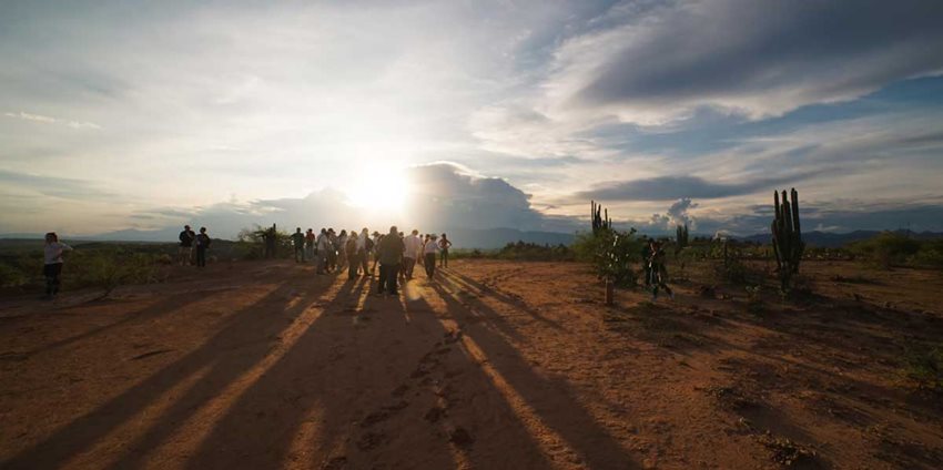 Descripción: Personas en medio del desierto, apreciando un atardecer.