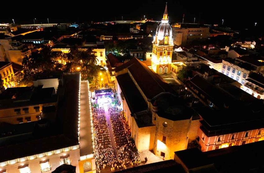 Descripción: Panorámica de la Torre del Reloj en Cartagena, de noche, con personas reunidas.